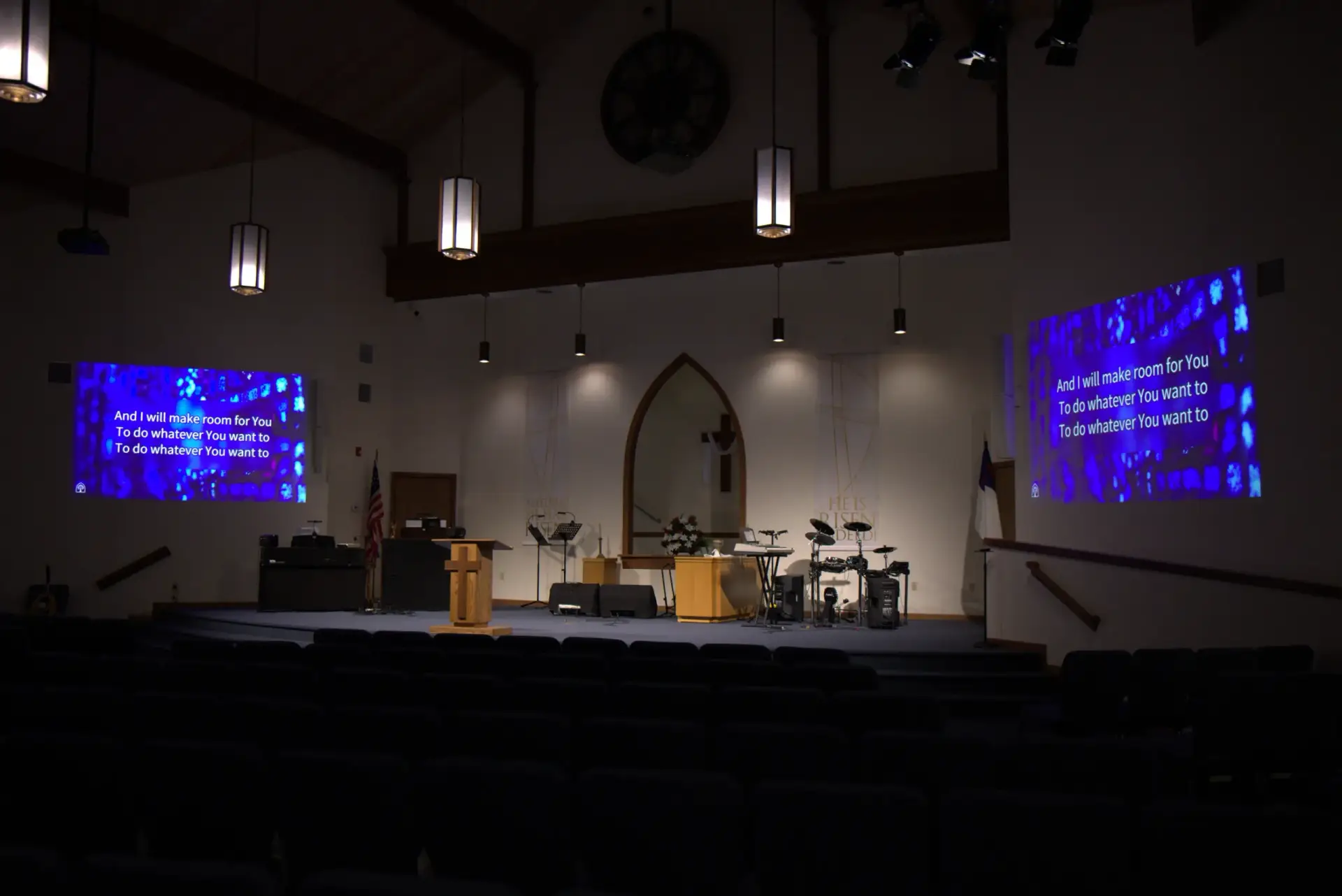 Wide view of a church sanctuary featuring dual projection screens, stage lighting, and AVL system installation by Presence Pro Audio
