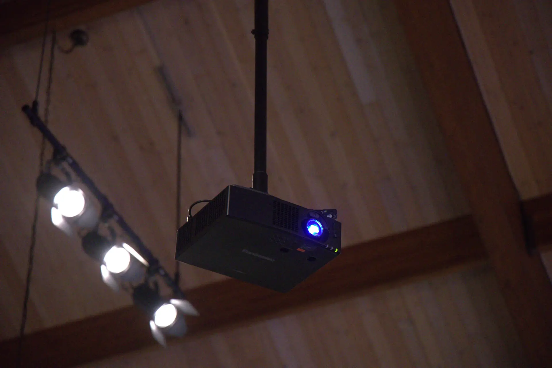 Close-up of a ceiling-mounted projector installed in a church sanctuary for worship presentation and livestream visuals