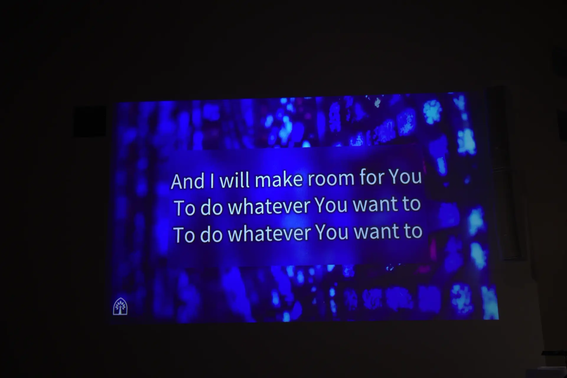 Church worship lyrics displayed on a large projection screen during a worship service