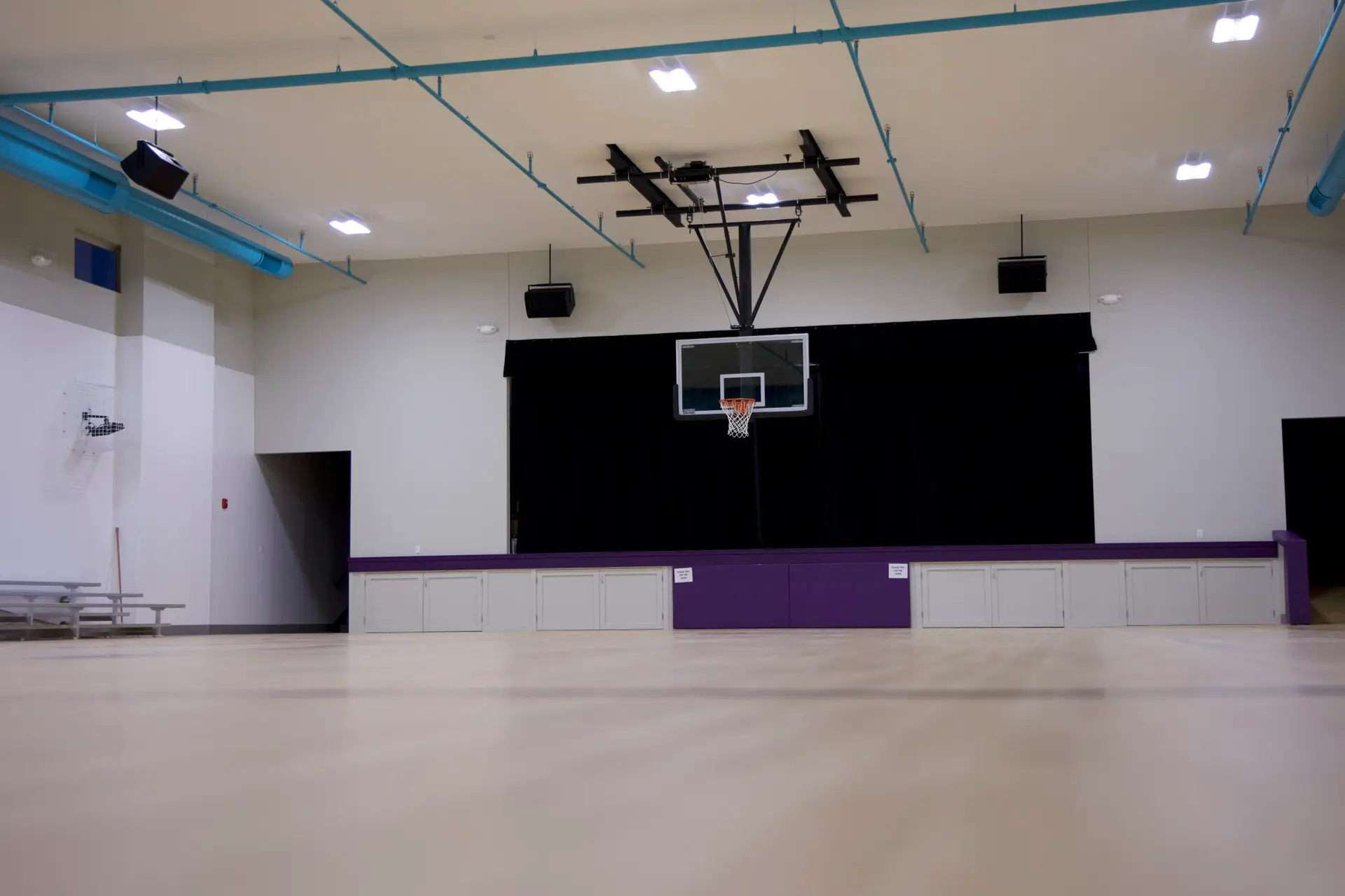 Wide view of suspended speaker layout installed throughout Covenant Christian School gymnasium auditorium
