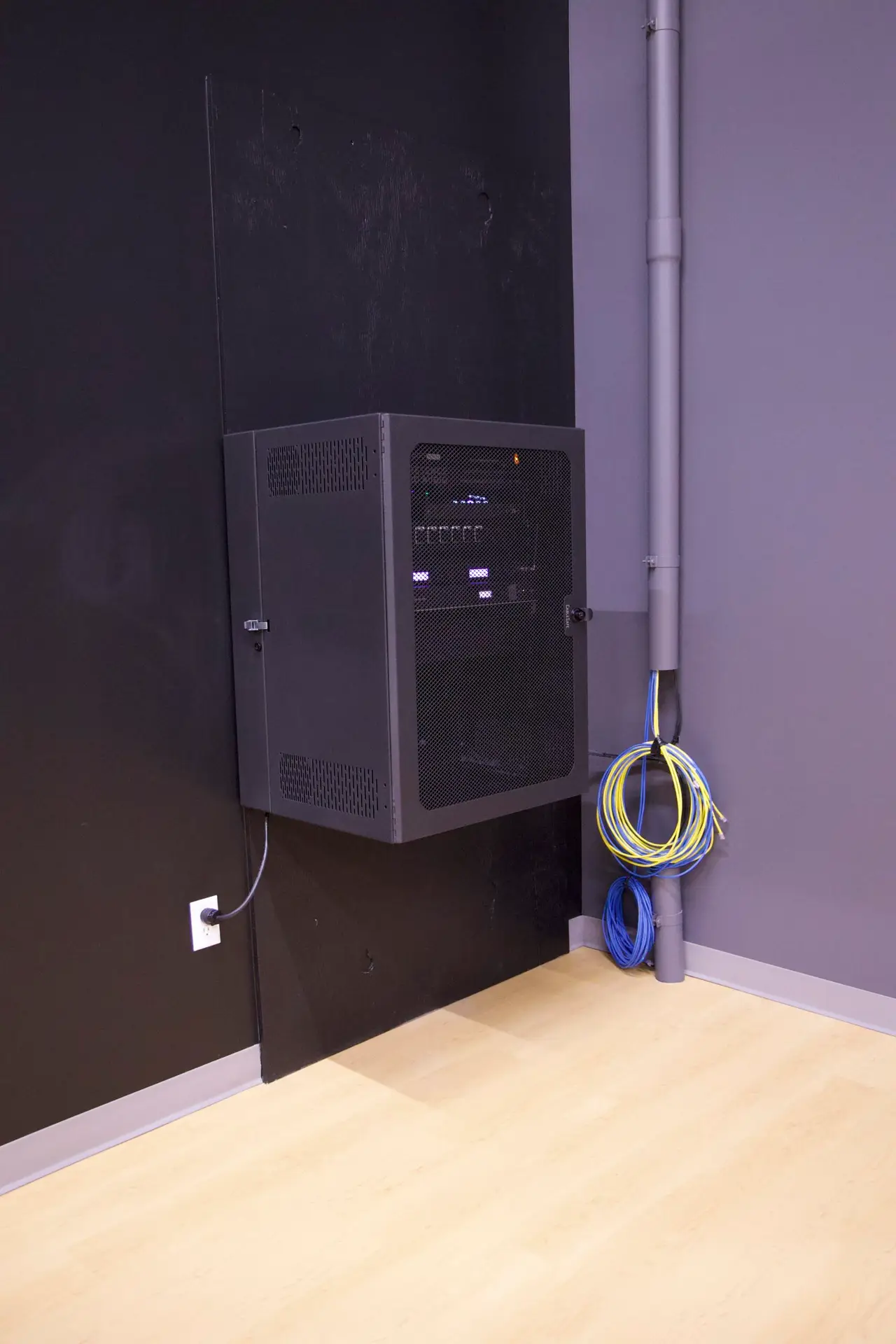 Side angle of custom wall-mounted AV rack system installed in school gymnasium auditorium